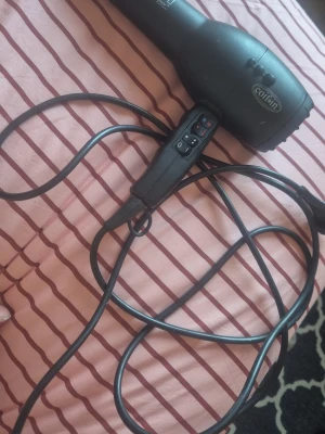 Svart hårfön från Coifin - En svart hårfön från Coifin med flera knappar för olika värme- och hastighetsinställningar. Hårfönen har en klassisk form och lång sladd, perfekt för styling och torkning av hår. Materialet är robust plast och designen är enkel och funktionell.