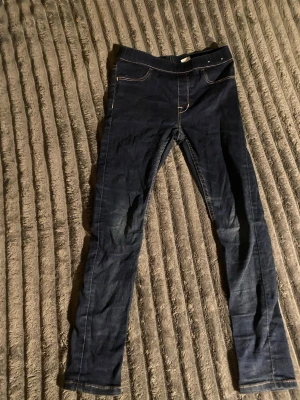 Mörkblå skinny jeans med kontrastsömmar - Snygga mörkblå skinny jeans med kontrastsömmar. Jeansen har smal passform och hög midja, perfekta till en avslappnad look. Materialet är stretchigt för extra komfort. Slitna över knäna.