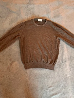 Brun tunn tröja från Rose & Born - Säljer en vintage brun tröja från Rose & Born i tunt, mjukt material. Tröjan har rund halsringning och långa ärmar. Perfekt för lager på lager och enkel att matcha med olika outfits.