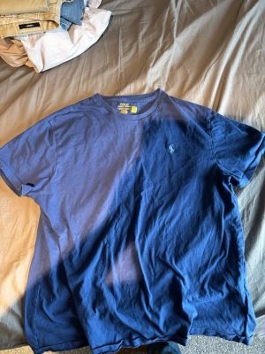 Blå t-shirt från Polo Ralph Lauren - Säljer en klassisk blå t-shirt från Polo Ralph Lauren med rund hals och korta ärmar. T-shirten har den ikoniska broderade loggan på bröstet och är gjord i mjuk bomull för skön komfort. Perfekt till jeans eller shorts.