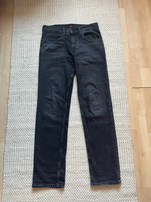 Mörkgrå raka jeans från Lee med riktigt snygg wash! - Sjukt snygga lee jeans modell ”west”. Köptes nya i butik och säljes pga att d va ett felköp och vill bara sälja de snabbt så därför får köparen en sjukt bra deal! Nypris-1200. Storlek 30/32. Gratis frakt!