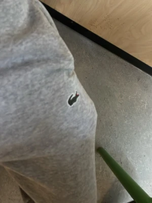 Gråa mjukisbyxor i bomull från lacoste  - Säljer ett par klassiska gråa mjukisbyxor i mjukt bomullsmaterial från lacoste. Byxorna har avslappnad passform och resår i midjan för extra komfort. Perfekta för chill dagar eller när du vill vara bekväm.