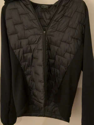 Svart pufferjacka med huva från Everest - Snygg svart pufferjacka med quiltat mönster och dragkedja framtill. Den är från Everest men sparsamt använd. Pytte pytte små defekter med de är absolut inget man märker.