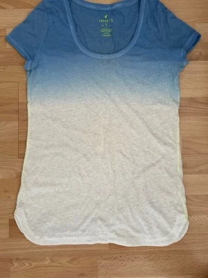 Blåvit t-shirt med ombre från H&M - Snygg t-shirt från H&M med ombre-effekt i blått och vitt. Modellen har rund halsringning och korta ärmar. Tillverkad i mjuk bomull som känns skön mot huden. Perfekt för dig som gillar en avslappnad och trendig stil. Lite nopprig under ärmarna.