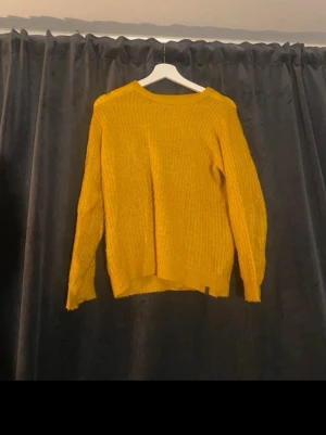 Gul stickad tröja med rund hals - Säljer en snygg gul stickad tröja med rund hals och långa ärmar. Tröjan har en avslappnad passform och är gjord i ett mjukt stickat material som är perfekt för att hålla dig varm. Enkel design som är lätt att matcha med olika outfits.