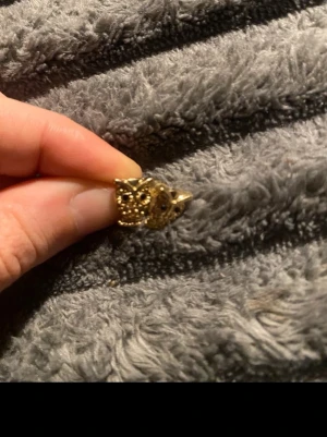 Guldiga uggleörhängen i metall - Säljer ett par guldiga örhängen formade som ugglor. De har detaljerade utskärningar och svarta stenar som ögon. Perfekta för dig som gillar djurmotiv och vill ha något unikt till din stil.