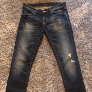 Nudie jeans  - Snygga mörkblå jeans från Nudie med slitna detaljer och en klassisk femficksdesign. Storlek 29/32
