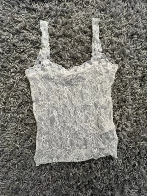 Vitt spetslinne - Säljer en vit, ärmlös linnetopp i genomskinlig spets. Storlek M från Nelly. Perfekt att styla lager på lager eller till ett par jeans. Skriv om du undrar något💕