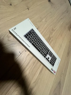 Satechi Slim X3 Bluetooth-tangentbord - Slim X3 Bluetooth-tangentbord från Satechi med bakgrundsbelysta tangenter. Tangentbordet är svart med silverram och har en smal, modern design. Kan kopplas till upp till fyra enheter samtidigt och passar perfekt till både Mac och PC.