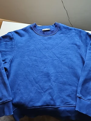 Blå sweatshirt från Zara - En stilren blå sweatshirt från Zara i storlek S. Tröjan har rund halsringning, ribbade muddar vid ärmslut och nederkant samt en enkel, klassisk design utan tryck eller mönster. Perfekt för en avslappnad look och lätt att matcha med jeans eller joggers.