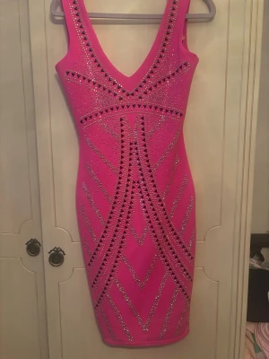 Rosa glittrig kortklänning från Lova - Säljer en superfin rosa kortklänning från Lipsy med glittriga paljettdetaljer och geometriskt mönster. Klänningen har v-ringning både fram och bak och är figurnära med stretchigt material. Perfekt för dig som vill sticka ut!
