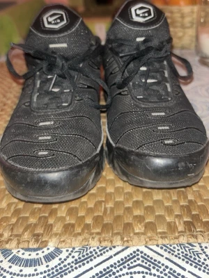 Svarta Nike sneakers med meshdetaljer - Snygga svarta sneakers från Nike med lågt skaft och coola meshdetaljer. Skorna har svarta skosnören, robust sula och vita logodetaljer på plösen. Perfekta för dig som gillar sportig och stilren look.