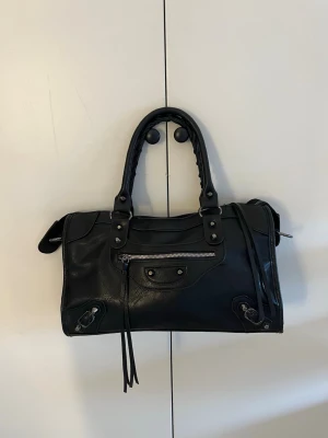 Balenciaga liknande väska  - Super snygg svart väska som är helt ny. Inga defekter förekommer. Man får med ett längre band som är justerbart men även avtagbart.