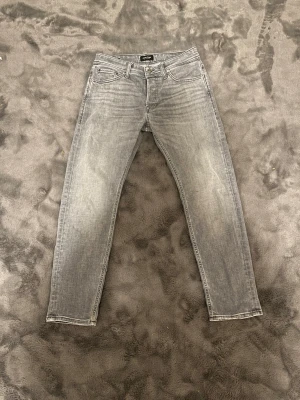 Grå Jack & Jones jeans - Säljer ett par grå jeans från Jack & Jones med klassisk femficksmodell och raka ben. Passar till alla tillfällen och outfits. Jeansen är använda fåtal gånger. Storlek W30 L30