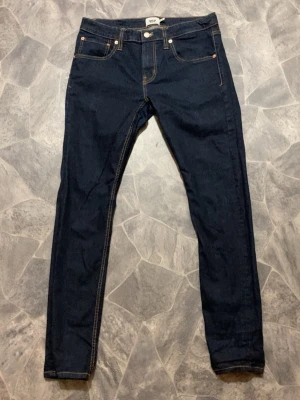 Mörkblå skinny jeans från 157 - Snygga mörkblå skinny jeans från 157 med klassisk femficksmodell och kontrastsömmar. Jeansen har en rak passform och är tillverkade i ett stretchigt denimtyg för extra komfort. Perfekta för dig som gillar en enkel och stilren look.