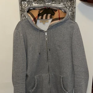 Grå Burberry hoodie med dragkedja - Snygg grå hoodie från Burberry med rutigt foder i huvan. 