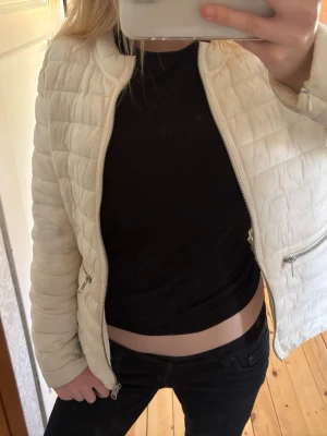 Vit pufferjacka med dragkedjor - Säljer en stilren vit pufferjacka med quiltat mönster och två snedställda dragkedjefickor framtill. Jackan har en rundad krage och silverfärgade detaljer. Perfekt nu till våren!💕