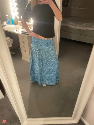 Blå långkjol med mönster - Säljer en blå långkjol med vitt mönster. Perfekt till stranden. Pris går att diskutera💕