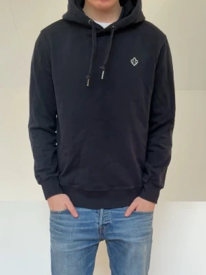 Mörkblå Morris Hoodie - Säljer en fet mörkblå hoodie från Morris i färgen mörkblå. Hoodien är i bra skick utan nåra defekter och sitter är i strl M men sitter i strl S. Hör gärna av er vid frågor elr funderingar!!