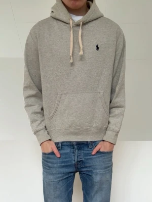 Grå Ralph Lauren hoodie - Säljer en Polo Ralph Lauren Hoodie i färgen grå. Hoodien är o strl M men sitter som en S. Den är i bra skick förutom att den har sminkfläckar där bak i luvan men ör inget som syns. Hör gärna av er vid frågor elr funderingar!!
