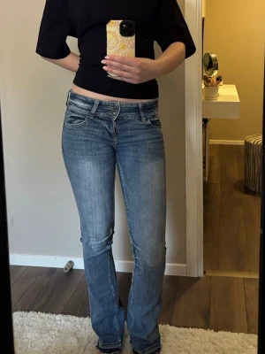 Blå bootcut jeans från Bershka - Snygga blå bootcut jeans från Bershka med en låg midja i storlek 32🥰😊.