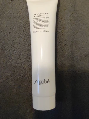 AHA Glycolic Peeling Gel Jorgobé - AHA Glycolic Peeling Gel från Jorgobé i en vit tub på 65 ml. Gelen exfolierar huden och ger lyster med hjälp av glykolsyra. Förpackningen är stilren och enkel med svart text. Perfekt för dig som vill ha en fräschare hudkänsla.