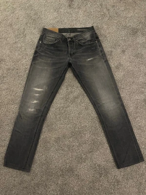 Dondup George W30 - Säljer ett par grå jeans från dondup med slitningar på framsidan. Jeansen är skinny fit och har en smal passform och är tillverkade i denim med lätt stretch. Perfekta för en avslappnad och trendig look. Hör av dig vid minsta lilla fundering, eller prisförslag.