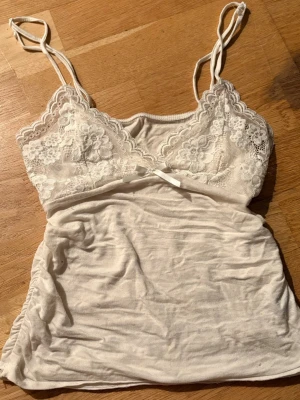 Vit spetslinnetopp med rosett - Fint litet vit linne men snygga detaljer