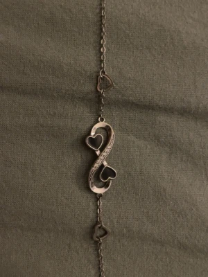 Silverfärgat armband  - Snyggt armband i silverfärg med en infinity-symbol dekorerad med två svarta hjärtan och små gnistrande stenar😽 Jättesnyggt och passar till allt<3