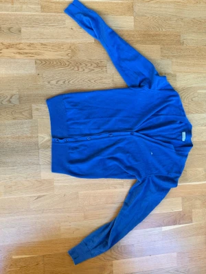 Otrolig stilren cardigan från J Lindeberg  - Factory New J.Lindeberg piké – 100% Merino ull Genuint otroligt fin blå piké från J.Lindeberg i 9/10 minimal wear skick. Den har en pytteliten lagning på insidan som inte syns alls utifrån – annars ser den ut som ny. Inga noppor, inga fläckar, inga slitage på utsidan.  Säljer för att den är lite liten på mig som 188cm & 95kg – perfekt om du vill ha en tight och stilren look.  Nypris ligger runt 1200 mitt pris 449! Hör av dig om du har frågor! Pris kan diskuteras vid snabb affär✅✅