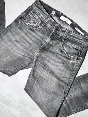 Grå jeans från Replay - Snygga grå jeans från Replay med tvättad look och klassisk femficksmodell. Jeansen har normal midja, knappgylf och Replay-logga på myntfickan.