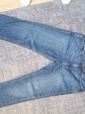 Blå jeans från Jack & Jones - Säljer ett par klassiska blå jeans från Jack & Jones, modell Regular/Clark. Jeansen har rak passform, fem fickor och snygga kontrastsömmar. Tillverkade i slitstarkt denimtyg som passar perfekt till vardagslooken. Använder inte byxorna längre för att jag bytte klädstil
