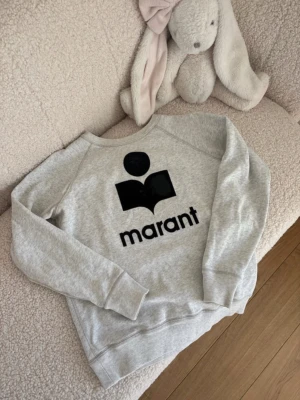 Grå sweatshirt från Isabel Marant - Sả fin. Säljer dà den inte kommer till användning. Sänkt pris dà "fluffet" har kommit av pa loggan och det finns lite missfärgningar vid lappen och insidan av nacken. Se bilder for mer information!🤗💝