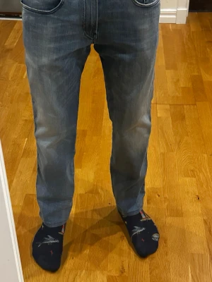 Replay jeans - Blå jeans med ljus tvätt från Replay, modell Anbass Hyperflex, i storlek W31 L30. Jeansen har en slim fit-passform och är uppsydda några centimeter, så jämför gärna med måtten – särskilt längden på 90 cm. Personen på bilden är cirka 180 cm som referens. Skicket är extremt bra. Nypris ligger på 1500 kr. Måtten är: midjemått 40 cm och längd 90 cm.  Kolla gärna in profilen också, där finns flera märkeskläder och skor – du hittar säkert något mer som passar 😉💯 Hör av dig om du undrar något!