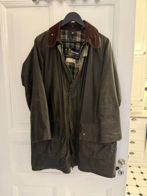 Barbour Gamefair 102cm, 40in. (M) vintage 1980s - Otroligt fint vintage barbour gamefair från 1980-talet i storlek 102 cm/40 in som motsvarar M ungefär. Otroligt fint skick för sin ålder. Ett litet hål vid dragkedjan och ett hål i fickan. Finns många lagningar men de är diskret utförda och bara på ställen så det inte syns, bara under armar.