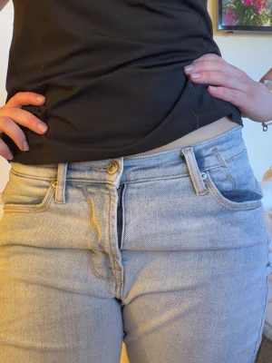 Ljusblå raka jeans med medel hög midja - Säljer ett par ljusblå bootcut jeans med medel hög midja. Klassisk femficksmodell med bälteshällor och dragkedjegylf. Jeansen har en avslappnad passform och är tillverkade i denim. Perfekta för en chill och trendig look.