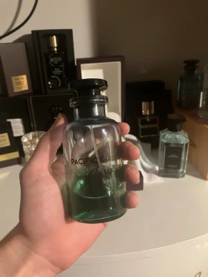Pacific chill - Lyxig parfym från Louis Vuitton, Pacific Chill, i en stilren glasflaska med svart lock. Flaskan har en transparent design med grönblå vätska och tydlig logga på framsidan. Perfekt för dig som gillar exklusiva dofter och snygg design. C 30 ml kvar ingen presentation kvar 