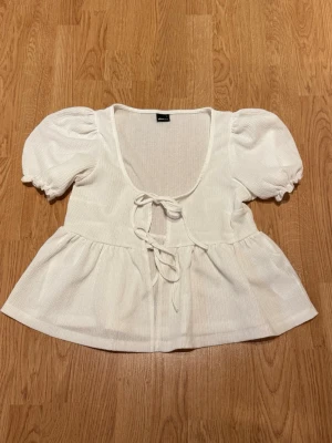Vit blus med puffärm och knyt - Supersöt vit blus med puffärmar och två knyt framtill. Har aldrig använt den!!💕