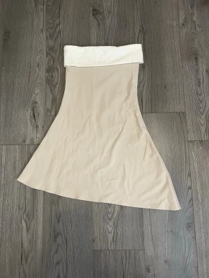 Beige klänning med vit linning - Snygg beige klänning med bred vit linning.Perfekt för dig som gillar stilrena och minimalistiska plagg. Den är i storlek S och köptes för 850kr, eftersom den inte finns att köpa helt ny löngre så säljer jag den för 850. Priset är inte hugget i sten så kom med bud och funderingar. Plagget är helt nytt aldrig andvänt.