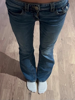 Blå bootcut jeans med låg midja - Säljer ett par blå bootcut jeans med låg midja och femficksmodell. Jeansen har en snygg tvättad look. De är från Gina tricot i storlek 164.