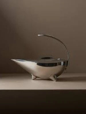 Tekanna Naoko - Design av Karsten Jörgensen för Bodum. Unik kanna i blankt silverfärgat metallmaterial med spetsig, modern form och ett elegant handtag som böjer sig över toppen. Kannan står på små ben och har ett lock på ovansidan. Perfekt som dekorationsföremål eller till servering.