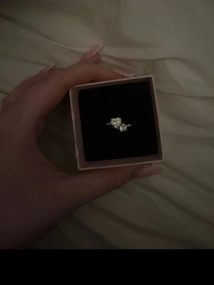 Pandora ring med två hjärtan  - Säljer en snygg silverfärgad ring med flera glittrande stenar i olika storlekar på rad. Ringen har en elegant och modern design som verkligen fångar ögat. Perfekt accessoar för dig som gillar stilrena smycken med lite extra bling.