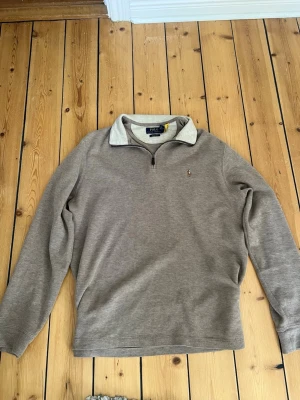 Polo Ralph Lauren beige långärmad tröja - En enkel och stilren beige långärmad polo Ralph lauren  tröja i mjukt material. Perfekt för en avslappnad och clean look. Passar till det mesta och är lätt att matcha med andra plagg. Passar perfekt för dig som är runt 175-180 mc lång. Nypris=1800
