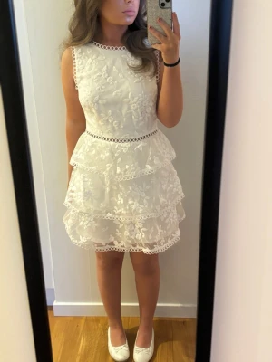 Superfin vit studentklänning- Lulus🌸 - Superfin vit studentklänning med vackra detaljer från Lulus 🤍 Klänningen har ett sött blommönster i spets/struktur och flera fina volanglager som ger en feminin och luftig stil. Den stora öppna ryggen är en väldigt fin detalj som ger klänningen det lilla extra. Modellen säljs inte längre vad jag vet. Storlek S, men passar XS också. Klänningen är i nyskick och endast provad. Skriv gärna till mig vid frågor🌸