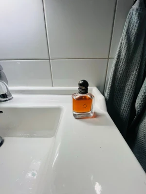 Stronger with you  - Säljer en stilren parfym i en fyrkantig glasflaska med rund silverfärgad kork. Doften har en varm bärnstensfärgad vätska som ger ett lyxigt intryck. Perfekt för dig som vill ha en klassisk och tidlös parfymflaska i badrummet.