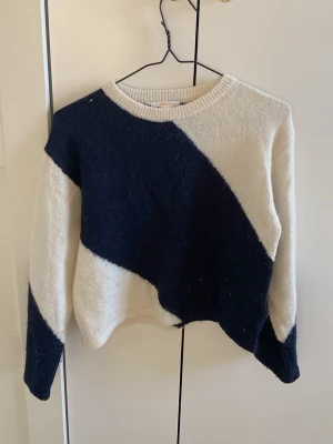 Stickad tröja Gina Tricot  - Säljer en snygg stickad tröja från Gina Tricot i storlek 146/152. Tröjan har ett coolt mörkblått & vitt blockmönster, rund halsringning och långa ärmar. Perfekt för dig som gillar en trendig och bekväm stil.