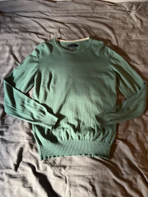Grön stickad tröja från Riley - Snygg grön stickad tröja från Riley i mjuk merinoull.  Storlek är L men sitter mer som M. Mitt pris 399. Hör av dig vid någon fråga!