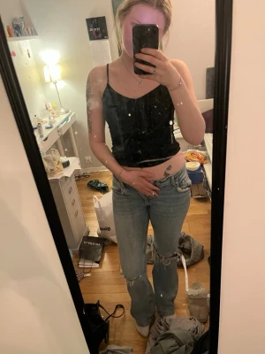 Ljusblå slitna bootcut jeans - Säljer ett par ljusblå bootcut jeans med slitningar på knäna och råa benslut. Jeansen har klassisk femficksdesign och hög midja. Perfekta för en avslappnad och trendig look.