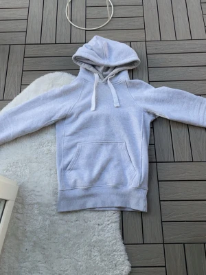 Grå Russemerch hoodie  - Säljer en ljusgrå hoodie från Russemerch i storlek XS. Hoodien har en klassisk känguruficka, dragsko i huvan och ribbade muddar vid ärmar och nederkant. Mjuk insida i fleece och enkel, stilren design som passar till det mesta.