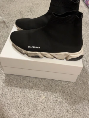  Speed Trainer svarta sneakers - Svarta Speed Trainer sneakers med vit logga på sidan. Strumpliknande ovandel i stretchigt tyg och tjock, vit sula med svarta detaljer. Modern och clean design som ger en sportig vibe.